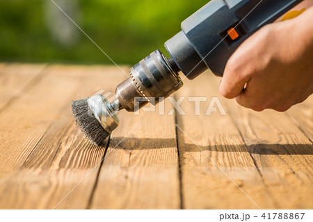 Hands man with electrical rotating brush metal disk sanding a piece of wood Hands man with electrical rotating brush metal disk sanding a piece of wood 41788867