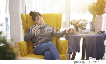 A young girl sitting in a big chair with a phone listening to music A young girl sitting in a big chair with a phone listening to music 41791460