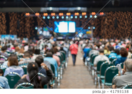 Abstract blurred photo of conference hall or seminar room in Exhibition Center with speakers on the stage and attendee background, seminar and study concept Abstract blurred photo of conference hall or seminar room in Exhibition Center with speakers on the stage and attendee background, seminar and study concept 41793138
