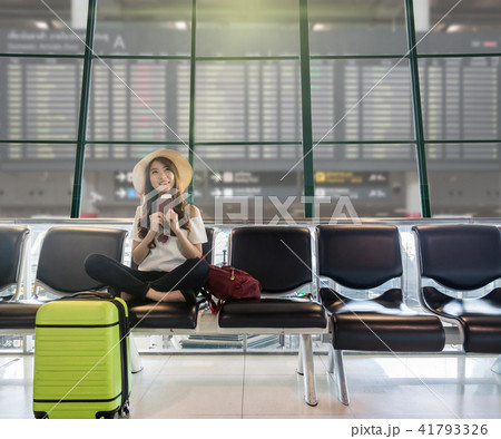 Happy Asian woman traveler holding the passport with suitcases and waiting for airplane arrive in modern an airport with travel information board background, travel and transportation concept. 41793326
