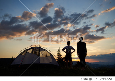 Back view silhouettes of female and kid stand near camping at daybreak Back view silhouettes of female and kid stand near camping at daybreak 41794728