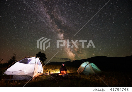Woman tourist resting at night camping under starry sky and Milky way Woman tourist resting at night camping under starry sky and Milky way 41794748