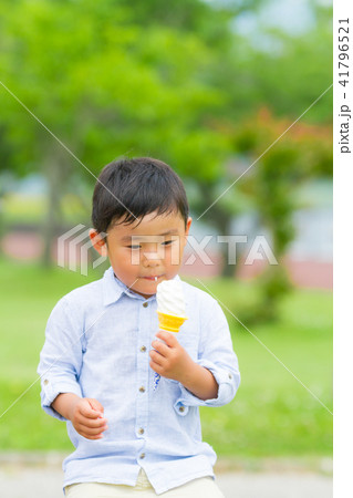 男の子 子供 公園 ベンチ ソフトクリーム 食べるの写真素材