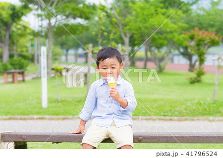 男の子 子供 公園 ベンチ ソフトクリーム 食べるの写真素材