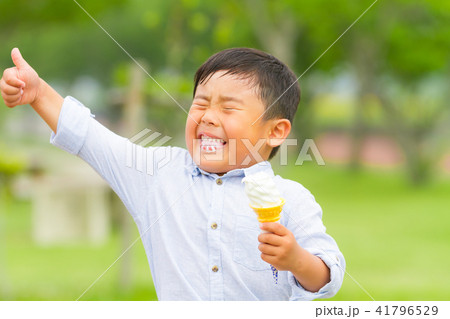 男の子 子供 公園 ベンチ ソフトクリーム 食べるの写真素材