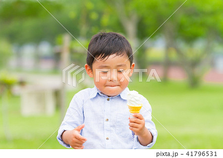 男の子 子供 公園 ベンチ ソフトクリーム 食べるの写真素材