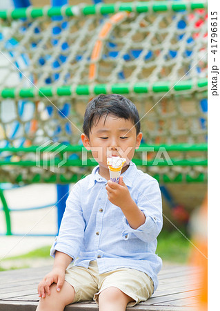 男の子 子供 公園 ベンチ ソフトクリーム 食べるの写真素材