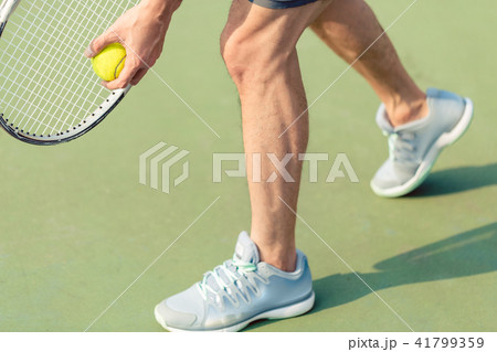 Low section of a professional player holding ball and tennis racket Low section of a professional player holding ball and tennis racket 41799359