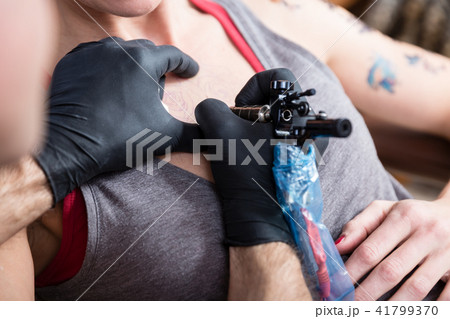Close-up of the hands of a tattoo artist tattooing two roses Close-up of the hands of a tattoo artist tattooing two roses 41799370