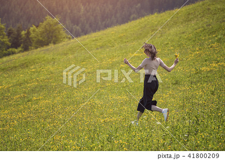 Girl with a bouquet is running on flower meadow Girl with a bouquet is running on flower meadow 41800209