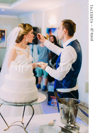 The groom is feeding the bride with the wedding cake. 41803741