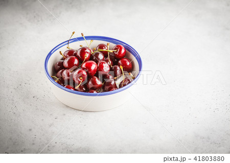 Ripe red cherry in a white bowl on a light Ripe red cherry in a white bowl on a light 41803880