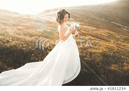 Beautiful bride with a bouquet on mountain background at sunset Beautiful bride with a bouquet on mountain background at sunset 41811234