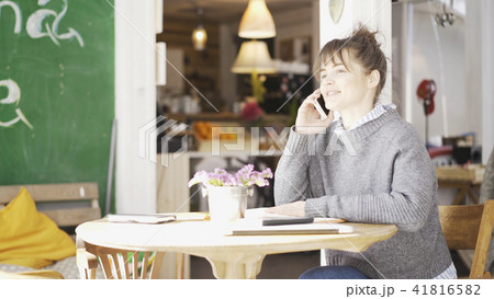 A young smiling cute brunette girl is having a call in a cafe 41816582