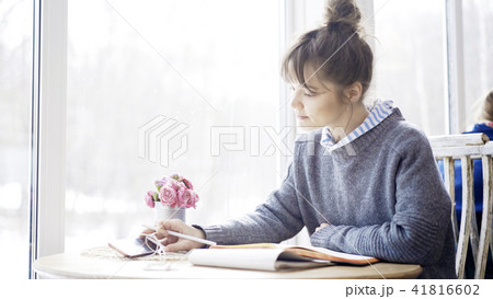 A young brunette girl is reading a notebook in the cafe A young brunette girl is reading a notebook in the cafe 41816602