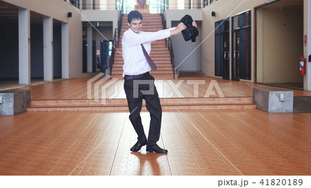 Young happy handsome businessman in a business suit with a briefcase dancing modern ballet against 41820189