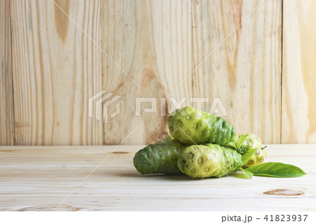 Noni fruit and leaves on wooden table and wooden b 41823937