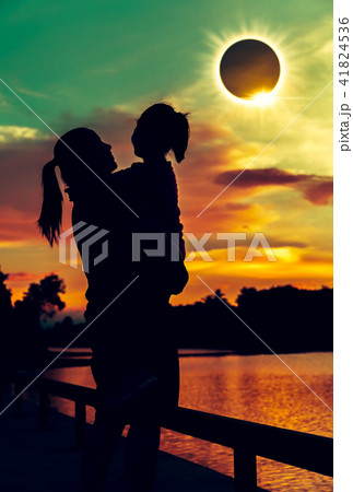 Mother and daughter look at solar eclipse on sky. 41824536