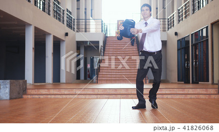 Happy handsome young businessman with a briefcase dancing in corporate lobby wearing suit 41826068