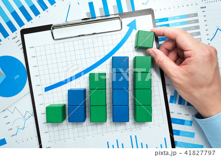 データ分析と事業の成長。多くのグラフを背景に積木を並べる手。 41827797