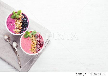 Two smoothie bowls with granola and berries. 41828169