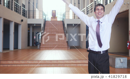 Happy young successful businessman stands with raising hands from joy in modern office. Concept of Happy young successful businessman stands with raising hands from joy in modern office. Concept of 41829718