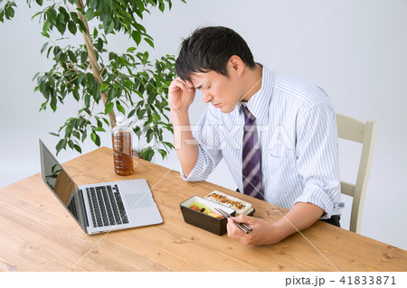 お弁当を食べながら仕事する男性(頭痛) お弁当を食べながら仕事する男性(頭痛) 41833871