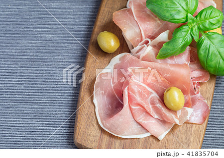 Prosciutto ham on wooden board with basil leaves 41835704