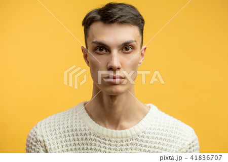 Portrait of a smart serious young man standing against yellow background 41836707
