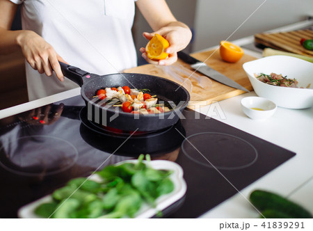 Cropped view of young happy housewife frying chicken meat for dinner 41839291
