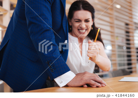 Indignant woman hitting mans hand with a pencil 41844160