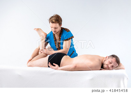 Theme massage and body care. A handsome Caucasian man in blue uniform and beard does stretching 41845458