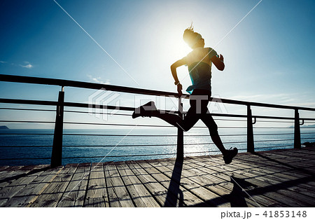 runner running on seaside boardwalk during sunrise runner running on seaside boardwalk during sunrise 41853148