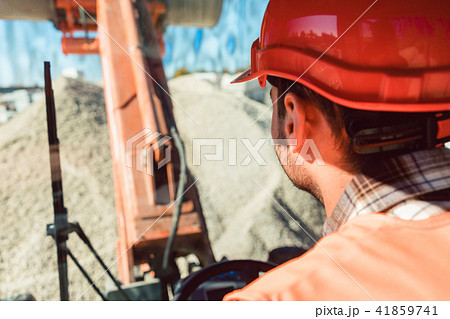 Worker on construction site operating wheel loader Worker on construction site operating wheel loader 41859741