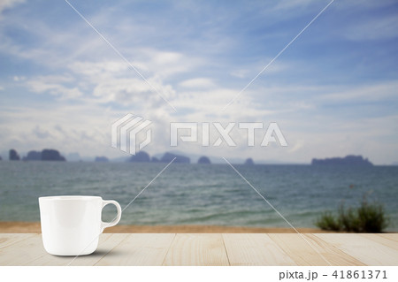 Hot coffee cup on wooden tabletop on blurred beach 41861371