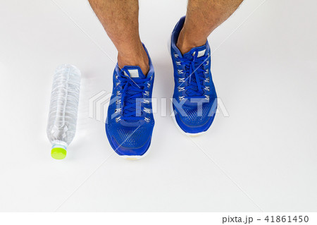 Legs, sport shoes and water bottle on white floor Legs, sport shoes and water bottle on white floor 41861450