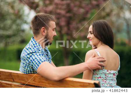 Young couple in love resting in the blooming garden. white blooming trees Young couple in love resting in the blooming garden. white blooming trees 41862443