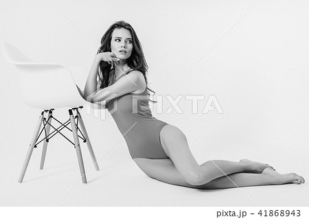 Woman in swimsuit leaning on chair Woman in swimsuit leaning on chair 41868943