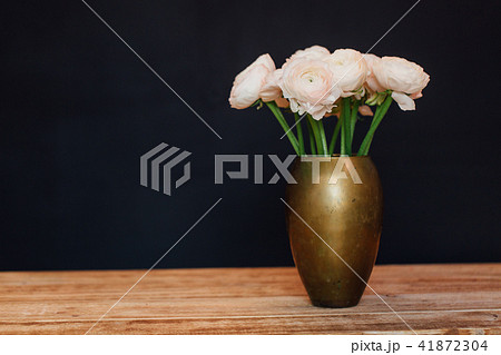 bouquet of pink delicate buttercups of flowers stands on a wooden table in a golden vase. bouquet of pink delicate buttercups of flowers stands on a wooden table in a golden vase. 41872304