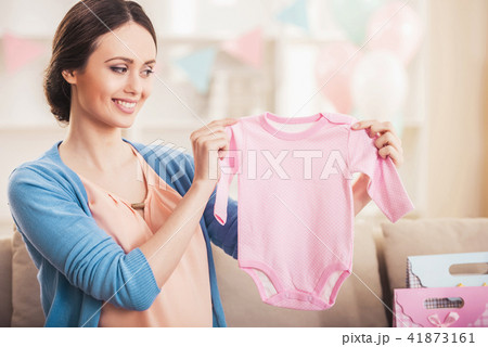 Smiling Pregnant Woman with Pink Baby Romper. 41873161