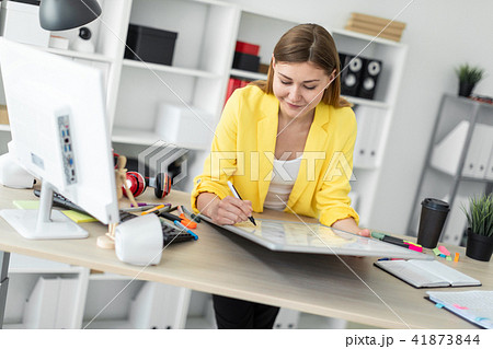A young girl stands near a table, holds a marker in her hand and works with a magnetic board. A young girl stands near a table, holds a marker in her hand and works with a magnetic board. 41873844