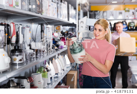 Young female is choosing new blender for his kitchen in store Young female is choosing new blender for his kitchen in store 41879131