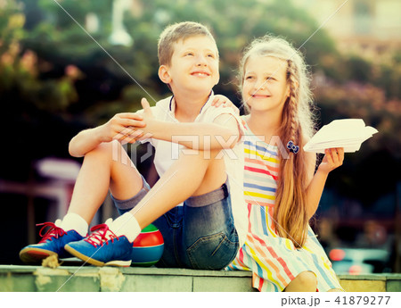 cheerful girl and boy sitting together in park 41879277