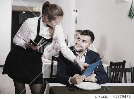 Welcoming female waiter is taking order from businessman in restaurante 41879476