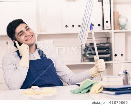 Man cleanaer is speaking on the phone instead of cleaning Man cleanaer is speaking on the phone instead of cleaning 41879866