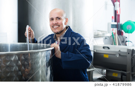 attentive mature man working in wine secondary fermentation section attentive mature man working in wine secondary fermentation section 41879986