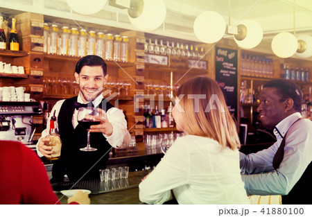 Bartender holding out glass with beverage Bartender holding out glass with beverage 41880100