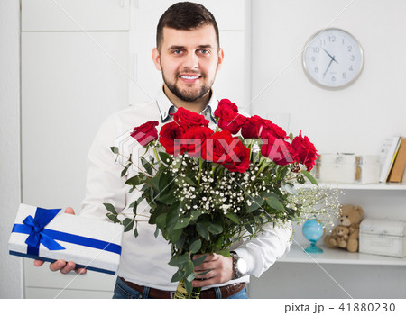 Positive young man congratulating woman with bouquet 41880230