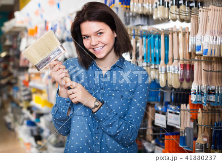 young girl deciding on brush for decorating house in paint store 41880237