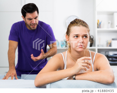 Stressed woman at table with screaming husband behind Stressed woman at table with screaming husband behind 41880435